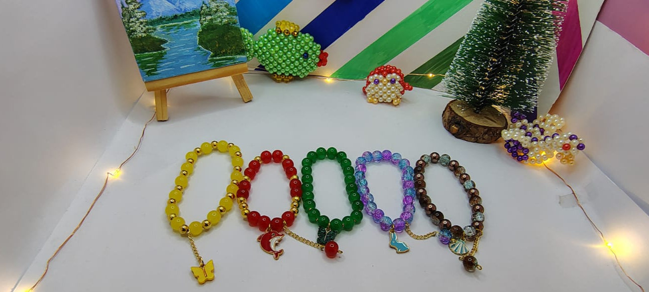 Set of colorful beaded bracelets on a white surface with decorative elements in the background.
